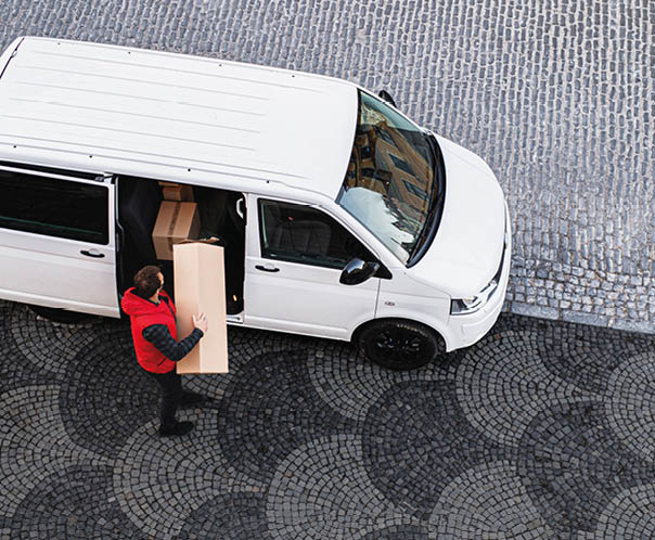 An aerial view of delivery man courier with face mask delivering parcel box in town.