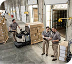 Uniformed warehouse workers loading boxed products into truck in a distribution warehosue.