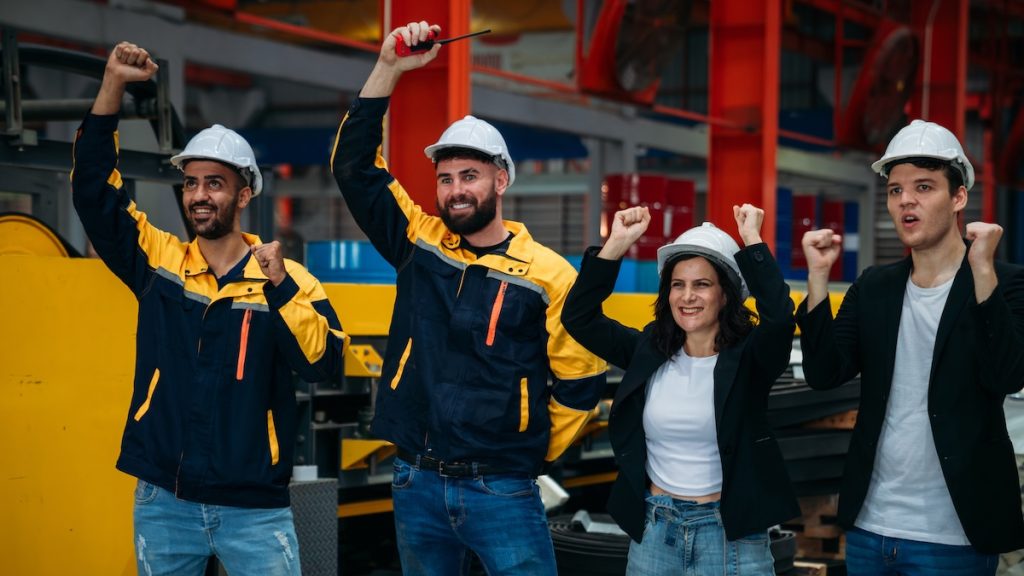 Team engineers and foreman stack hand and shake hands to show success at factory machines. Worker industry join hand for collaboration.